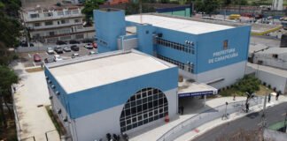 Carapicuíba abre prazo para pedidos de isenção do IPTU 2027-2029 Documento de IPTU e mãos de um idoso acessando o computador para isenção.