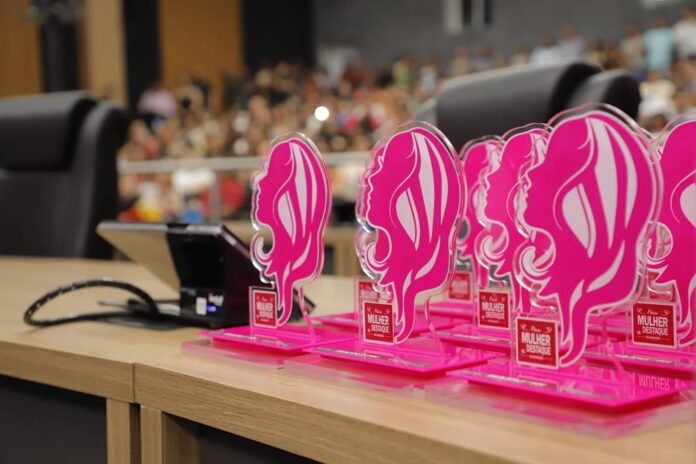 Mulher recebendo troféu em evento oficial da prefeitura de Barueri, representando o prêmio mulher destaque