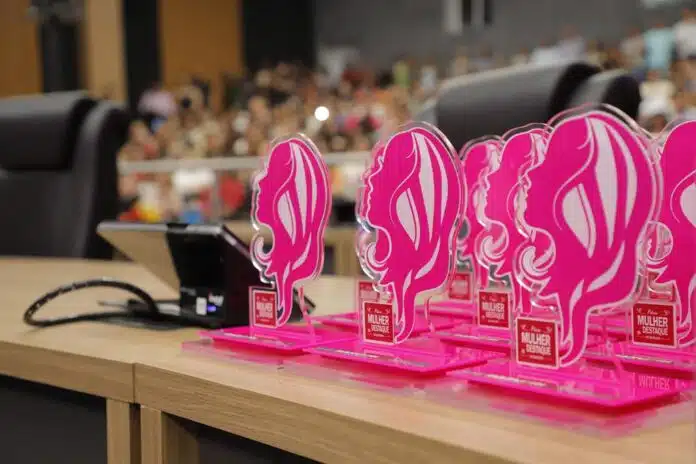 Mulher recebendo troféu em evento oficial da prefeitura de Barueri, representando o prêmio mulher destaque